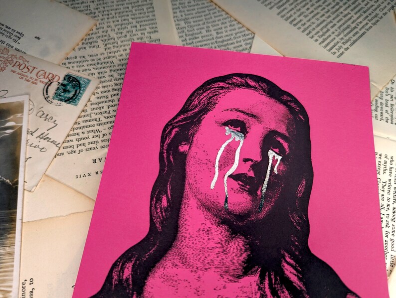 Puede incluir: Una impresi&oacute;n art&iacute;stica rosa con una ilustraci&oacute;n en blanco y negro de una mujer llorando. Las l&aacute;grimas est&aacute;n resaltadas en plata. La imagen est&aacute; rodeada de postales antiguas y p&aacute;ginas de libros.