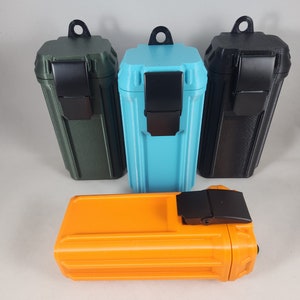 May include: Three small rectangular storage containers with lids and carrying loops. The containers are green, blue, and black. A fourth orange container with a black latch is in the foreground.