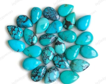 May include: A collection of turquoise gemstones in various shapes, including teardrops and ovals. The stones display a vibrant blue-green color with dark matrix patterns. The gemstones are arranged on a white surface.