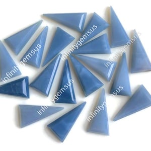 May include: A selection of triangular, pale blue gemstones. The gemstones have varying shades, with some appearing darker. The edges of the stones are smooth and polished, and the arrangement is scattered.