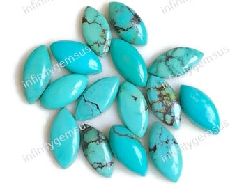 May include: A collection of turquoise gemstones, each with an oval shape and polished surface. The stones vary in color, with some displaying dark brown matrix patterns. The gemstones are arranged on a white surface.