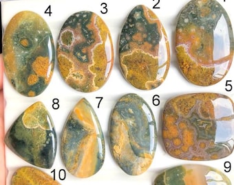 May include: A collection of ten polished gemstones in various shapes, including oval, teardrop, and rectangular. The stones display a mix of colors, such as green, yellow, and brown, with unique patterns and textures. These gemstones are ideal for jewelry making or collecting.