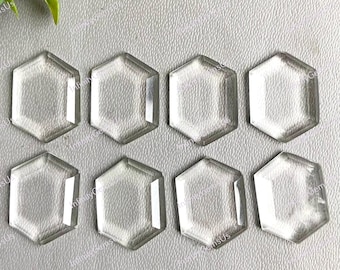 以下が含まれることがあります： 明るい灰色の表面に配置された8つの透明な六角形の宝石。 透明な石は研磨仕上げで、幾何学的な形状を際立たせています。 この配置は、ジュエリー作りや工芸品に使用される可能性のある、原石またはカットされたクリスタルのコレクションを示唆しています。