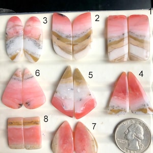 Puede incluir: Una colección de ocho pares de piedras preciosas pulidas en varias formas, incluyendo óvalos, rectángulos y triángulos. Las piedras muestran una mezcla de colores rosa, blanco y beige, con patrones en capas. Se incluye una moneda para referencia de tamaño.