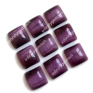 May include: Eight purple cat's eye gemstone cabochons, each with a square shape and a smooth, polished surface. The stones have a shimmering, iridescent effect.