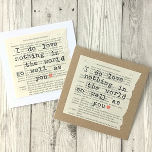 Op de afbeelding: Twee handgemaakte wenskaarten met tekst van een pagina uit een boek. E&eacute;n kaart is wit, de andere bruin. De tekst luidt "I do love nothing in the world so well as you" met een rood hart. De kaarten liggen op een licht houten oppervlak.