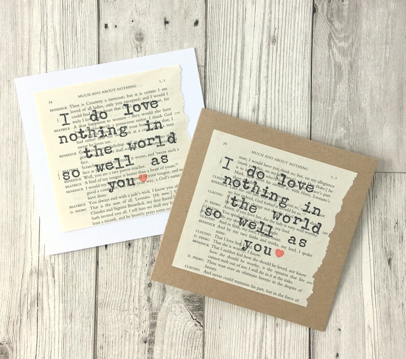 Op de afbeelding: Twee handgemaakte wenskaarten met tekst van een pagina uit een boek. E&eacute;n kaart is wit, de andere bruin. De tekst luidt "I do love nothing in the world so well as you" met een rood hart. De kaarten liggen op een licht houten oppervlak.