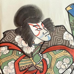 Puede incluir: Una pintura de un actor de kabuki japon&eacute;s que lleva un disfraz colorido con una t&uacute;nica de patr&oacute;n verde y dorado y una faja roja. El actor tiene la cara blanca con marcas rojas y azules y el pelo negro.