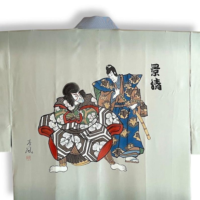 Puede incluir: Un kimono gris claro con una escena japonesa tradicional pintada en la espalda. La escena representa dos figuras con trajes elaborados, una sentada y otra de pie. El texto "長者" est&aacute; escrito en negro en el lado derecho del kimono.