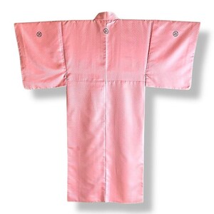 May include: A pink Japanese kimono with a traditional pattern. The kimono has a high collar and long sleeves. There are three small black circles on the back of the kimono.