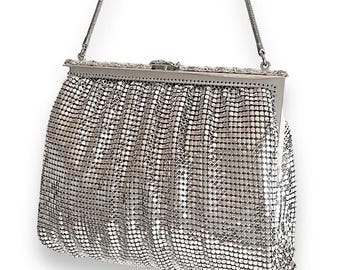 May include: A silver mesh evening bag with a chain strap and a silver clasp.