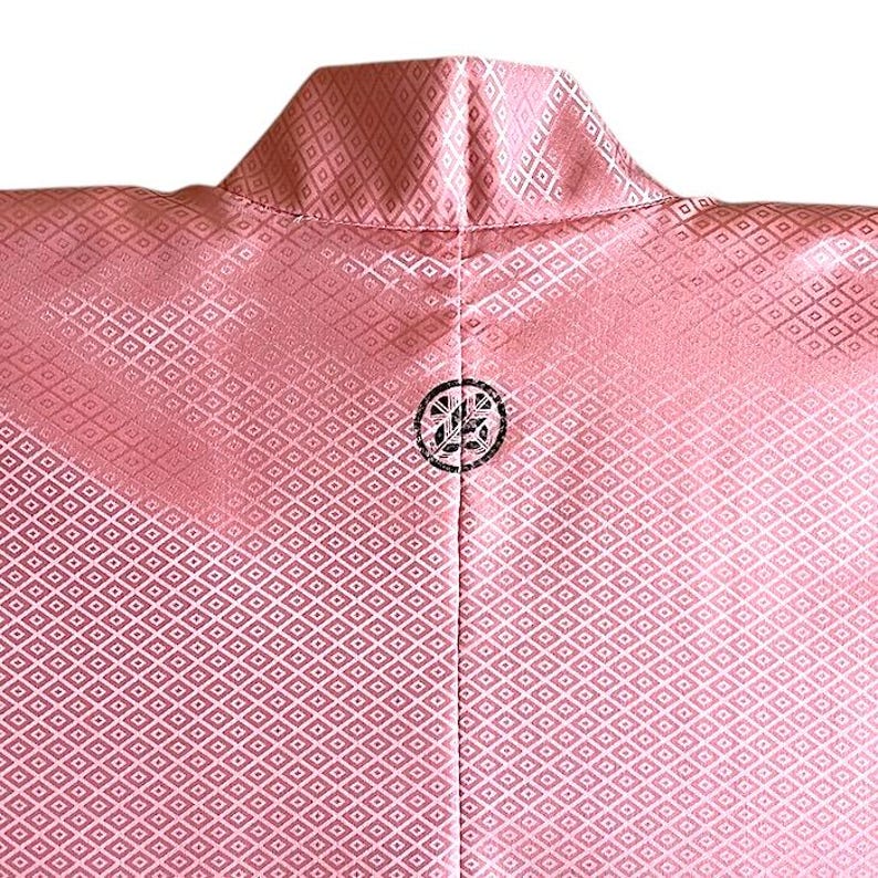 May include: A pink kimono with a white diamond pattern and a black crest on the back.