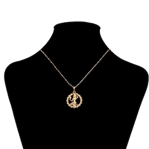 May include: A gold chain necklace with a pendant featuring a stylized figure of a woman. The pendant is round and has a detailed design.