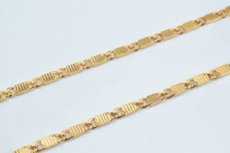 Puede incluir: Un collar de cadena de oro con un dise&ntilde;o de eslab&oacute;n rectangular texturizado.