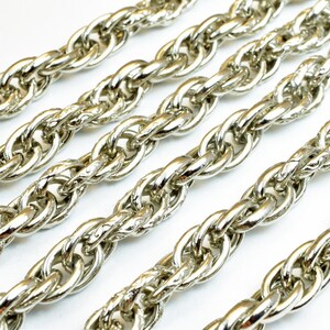 May include: Close-up of a silver chain with a twisted rope design. The chain is made of metal and has a shiny finish.
