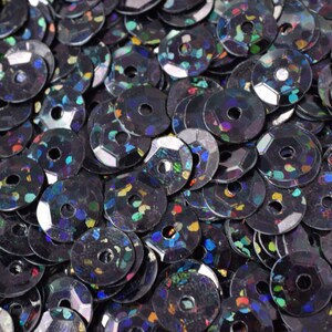 May include: A pile of iridescent black sequins with a small hole in the center of each sequin.