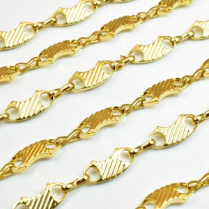 Op de afbeelding: Gouden ketting met een uniek visgraatontwerp. De ketting is gemaakt van gekoppelde, platte, ovale stukken met een getextureerd oppervlak.