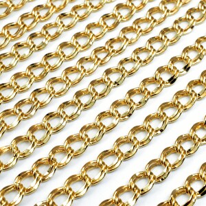 Puede incluir: Primer plano de una cadena de oro con un eslabón ovalado retorcido. La cadena está dispuesta en filas sobre una superficie blanca.