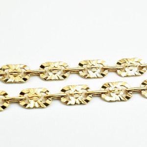 May include: A gold chain necklace with a patterned link design.