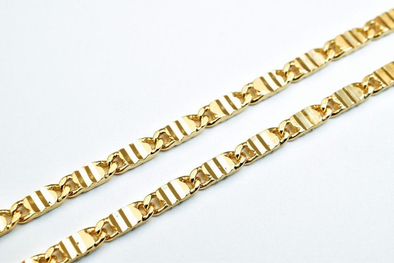 May include: A gold chain necklace with a textured, striped design. The chain is made of linked oval-shaped pieces.