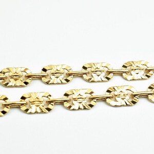 May include: A gold chain necklace with a patterned link design.