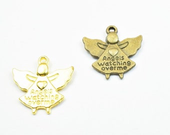 May include: Two gold angel charms with wings and a heart. The charm on the left is gold and the charm on the right is bronze. Both charms have the text "Angels watching over me".