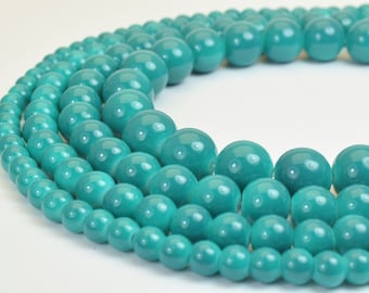 Peut inclure: Un collier de perles bleu turquoise. Les perles sont rondes et lisses, et elles sont disposées en cercle. Le collier est composé de plusieurs rangs de perles, les plus grosses étant sur le rang extérieur.