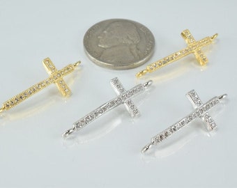 Puede incluir: Cuatro dijes de cruz de oro y plata con adornos de cristal transparente. Los dijes tienen un bucle en la parte superior para sujetarlos a un collar o pulsera.