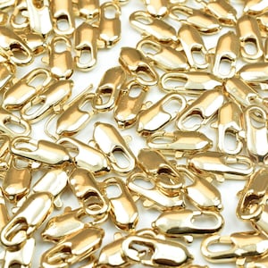 Puede incluir: Un gran grupo de cierres de langosta de metal dorado, comúnmente utilizados para la fabricación de joyas.