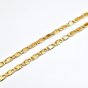 May include: A gold chain necklace with a textured, mariner link design.