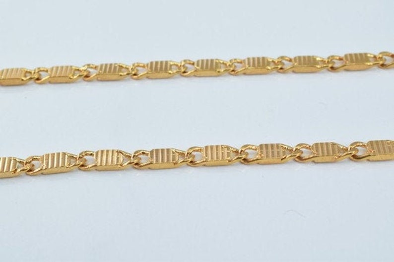 Puede incluir: Un collar de cadena de oro con un patr&oacute;n de eslabones rectangulares.