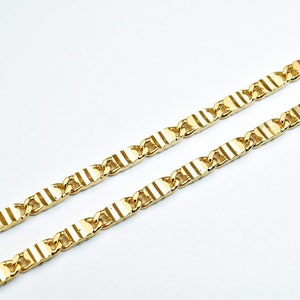 May include: A gold chain necklace with a textured, striped pattern. The chain is made of linked, rectangular pieces.