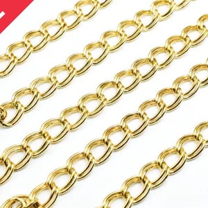 May include: Four strands of gold chain link, each with a slightly different length, are laid out on a white surface. The chain links are oval shaped and have a shiny, metallic finish.
