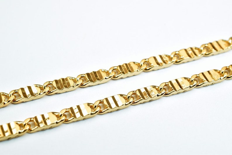 May include: A gold chain necklace with a textured, striped pattern. The chain is made of linked, rectangular pieces.