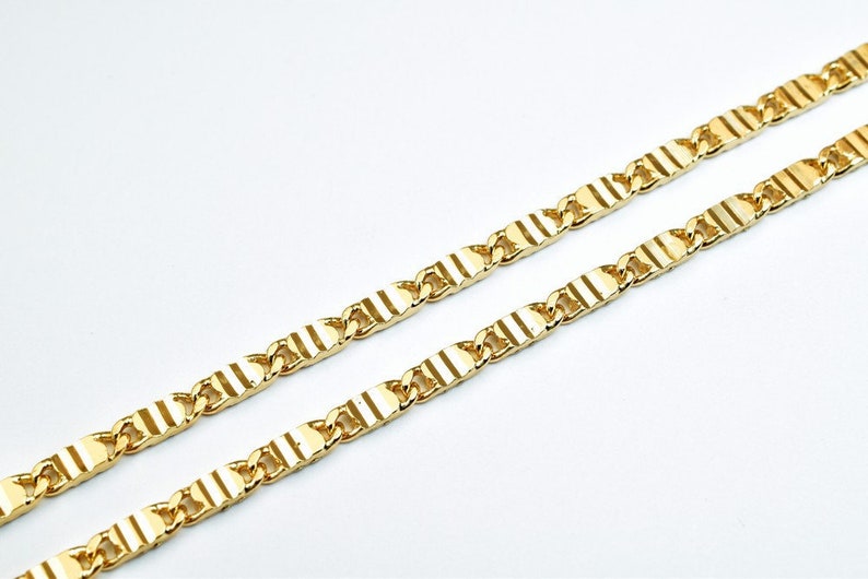 May include: A gold chain necklace with a textured, flat link design.