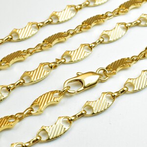 Op de afbeelding: Een gouden ketting met een textuur, visvormig schakeld ontwerp.