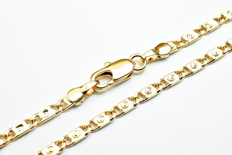 Puede incluir: Un collar de cadena de oro con cierre de mosquet&oacute;n. La cadena est&aacute; hecha de una serie de eslabones ovalados con un centro elevado.