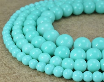 Peut inclure: Gros plan sur un brin de perles rondes bleu turquoise. Les perles sont disposées en cercle, les plus grosses au centre et les plus petites à l'extérieur.