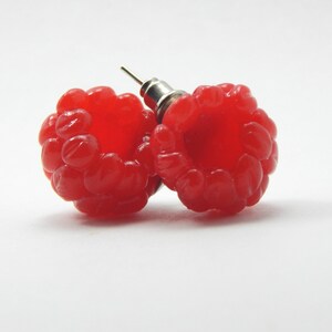 May include: A pair of red raspberry earrings. The earrings are made of polymer clay and are shaped like raspberries. They are attached to silver posts.