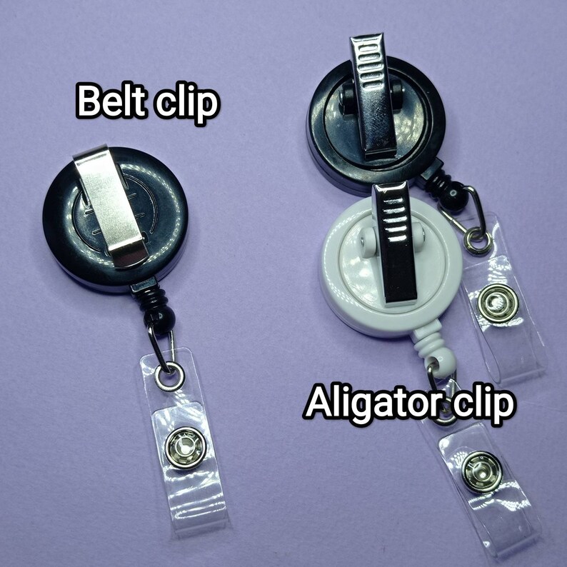 May include: Two retractable badge holders with different clips. The black holder has a belt clip and the white holder has an alligator clip. Both holders have clear plastic straps.
