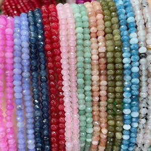 Puede incluir: Una colección de hilos de cuentas de piedras preciosas facetadas en varios colores, incluyendo rosa, azul, verde, rojo y blanco. Las cuentas están enhebradas en un hilo transparente y están listas para ser utilizadas en la elaboración de joyas.