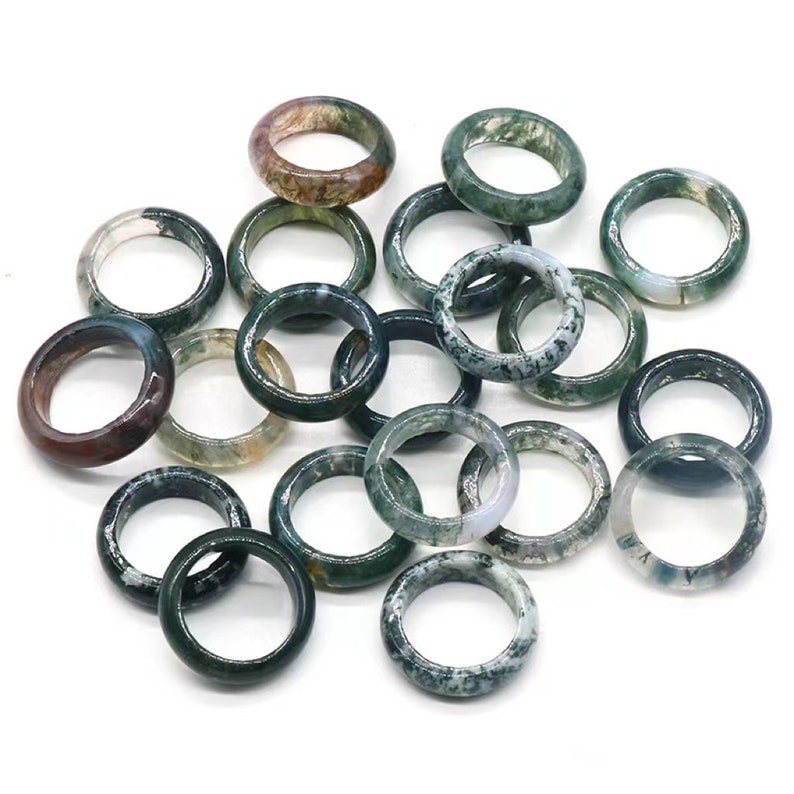 May include: A collection of green, brown, and white agate rings. The rings are all different sizes and shapes, but they all have a similar pattern of swirling colors.