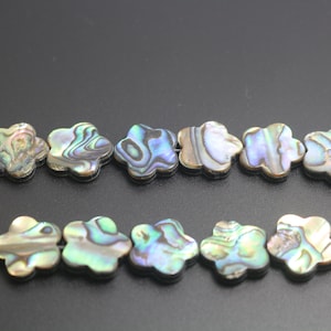 Può includere: Una collana di perle di madreperla di abalone iridescente a forma di fiore. Le perle sono un mix di verde, blu e viola.