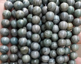 May include: A strand of round, green and gray patterned beads. The beads are made of a natural stone with a smooth, polished finish.