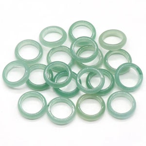 May include: A pile of 18 light green jade stone rings. The rings are smooth and polished.