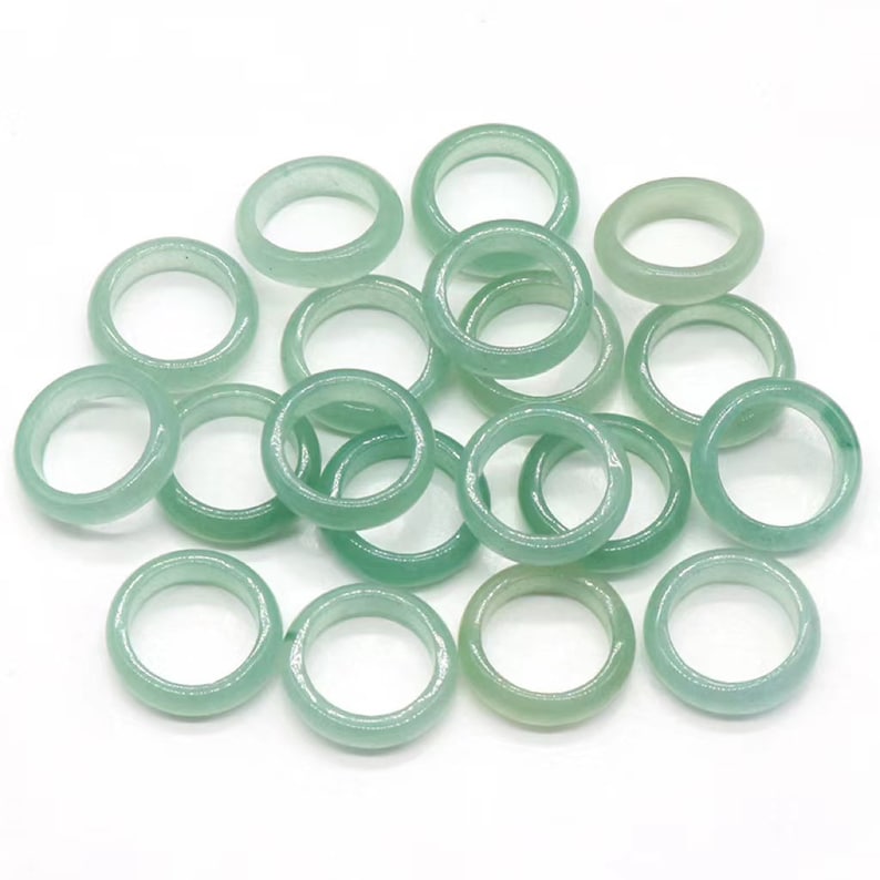 May include: A pile of 18 light green jade stone rings. The rings are smooth and polished.