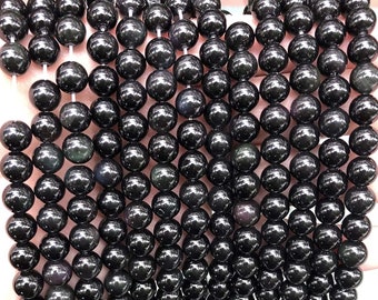 Könnte beinhalten: Eine Schnur aus schwarzen Obsidianperlen mit einem leichten irisierenden Schimmer. Die Perlen sind rund und glatt und auf einer durchsichtigen Schnur aufgefädelt.