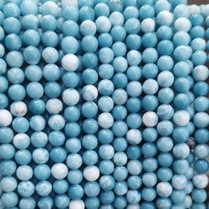 May include: A strand of light blue and white round gemstone beads. The beads are smooth and have a marbled appearance.