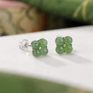 Peut inclure: Une paire de boucles d'oreilles à clous avec quatre pierres de jade vert clair rondes disposées en forme de trèfle. Les boucles d'oreilles ont des tiges et des fermoirs en argent.