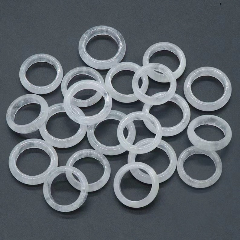 May include: A pile of white jade rings, each ring is smooth and polished. The rings are all different sizes and shapes, but they are all made of the same material.